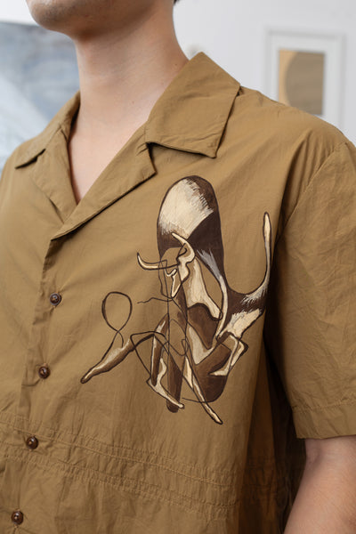 Close up right side view of tan bowling hand painted shirt featuring an abstracted bull and corozo button closure by nowhere studio