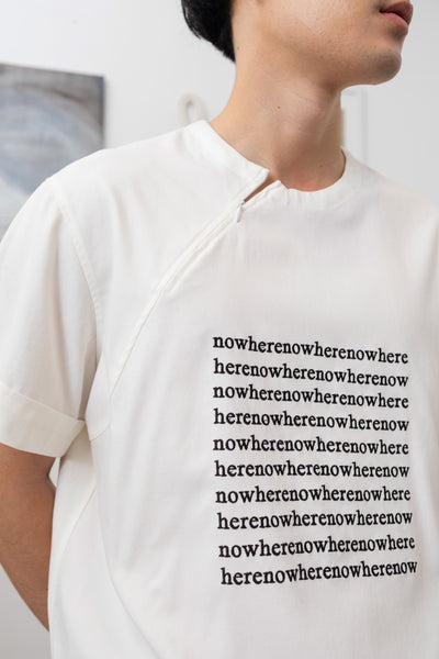 Detail of white menswear shirt with embroidered logo graphic and invisible zipper detail at neckline  by nowhere studio