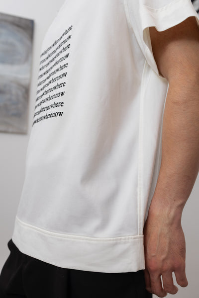 Alternate front detail of white menswear shirt with embroidered graphic showing reinforced seams and hem band by nowhere studio