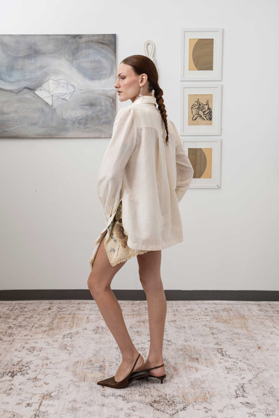 Sculptural blouse in ivory, left side view — cropped length with architectural drape and woven finish, nowhere studio