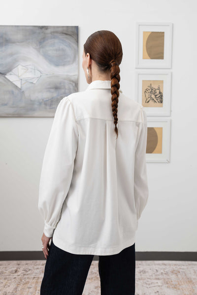 Close-up back left detail of sculptural blouse in white — construction detail with gathered volume and woven fabric, nowhere studio