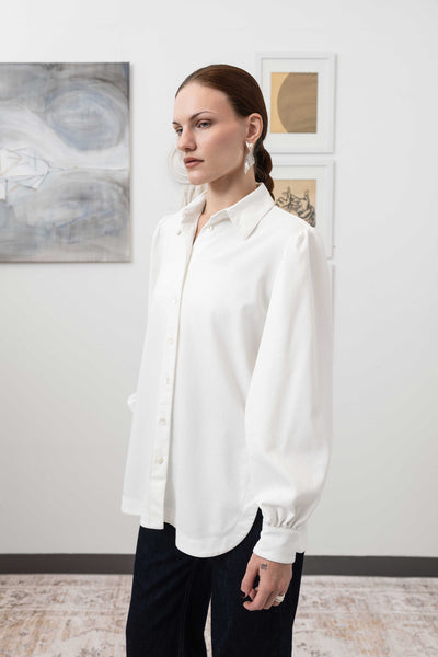 Close-up front left detail of sculptural blouse in white — structured volume with architectural silhouette, nowhere studio