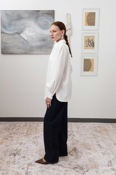 Sculptural blouse in white, left side view — cropped length with architectural drape and woven finish, nowhere studio