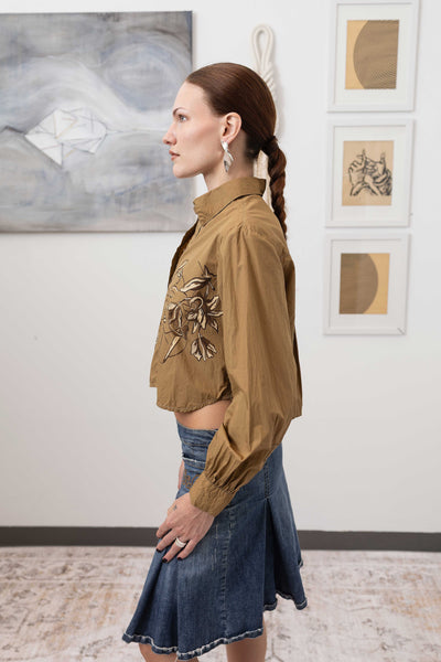 Close-up left side detail of hand painted artisanal blouse in tan — painted surface texture with gathered sleeve, nowhere studio