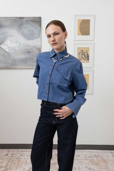 Close-up front view of utilitarian shirt in denim with contrast double-needle topstitching detail, nowhere studio