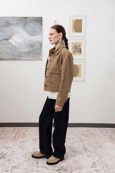 Workwear jacket in earth, left side view — shrunken proportions with selvedge fringe centre panel and reinforced seams, nowhere studio