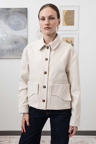 Close-up front view of workwear jacket in ivory — Corozo button closure and curved flap pocket detail, nowhere studio
