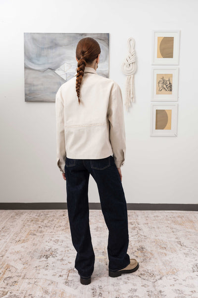 Workwear jacket in ivory, full back view — artisanal construction with textural selvedge fringe and structured hem, nowhere studio