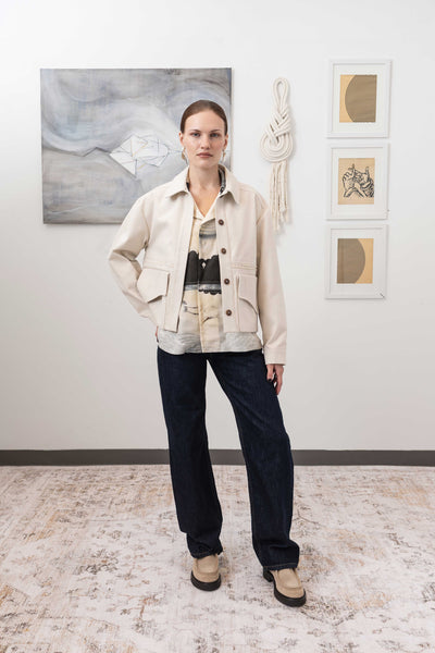 Workwear jacket in ivory, full front view — relaxed shrunken silhouette with selvedge fringe panel and Corozo buttons, nowhere studio