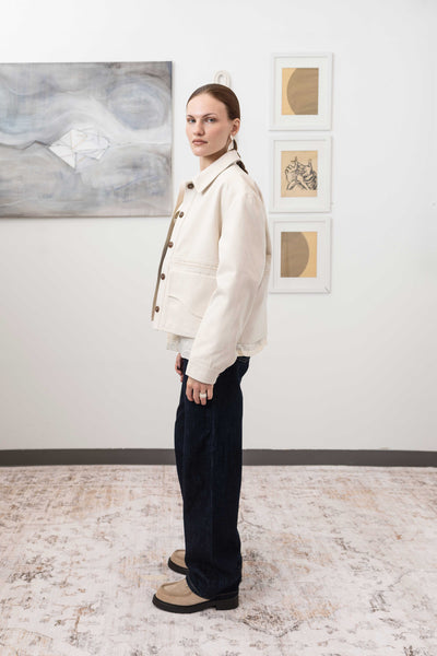 Workwear jacket in ivory, left side alternate view — shrunken silhouette with dual-entry pockets and Corozo button closure, nowhere studio