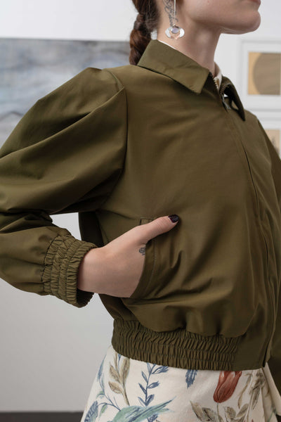 Side detail of sculptural blouson jacket in army — pleated sleeve volume with gathered waist seam in deadstock nylon, nowhere studio