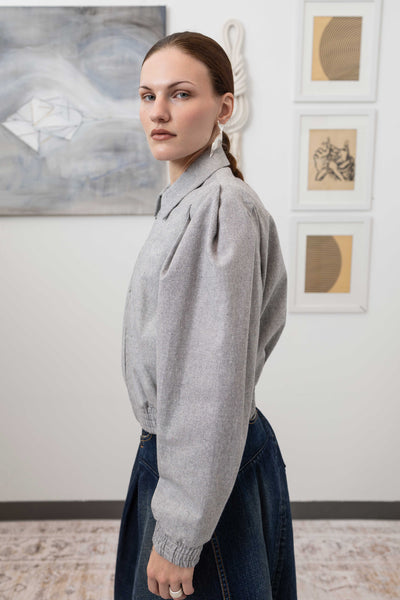 Close-up left side detail of sculptural blouson jacket in granite — pleated sleeve construction in mid-weight yarn-dye canvas, nowhere studio