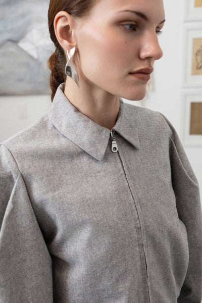 Front right detail of sculptural blouson jacket in granite — metal zip closure by nowhere studio