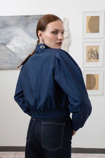 Close-up back right detail of sculptural blouson jacket in navy — gathered waist seam and water-resistant nylon finish, nowhere studio