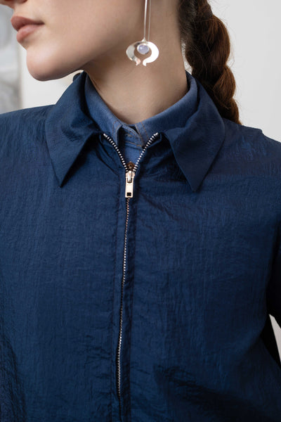 Collar detail of sculptural blouson jacket in navy — structured neckline with metal zip in crinkled nylon, nowhere studio