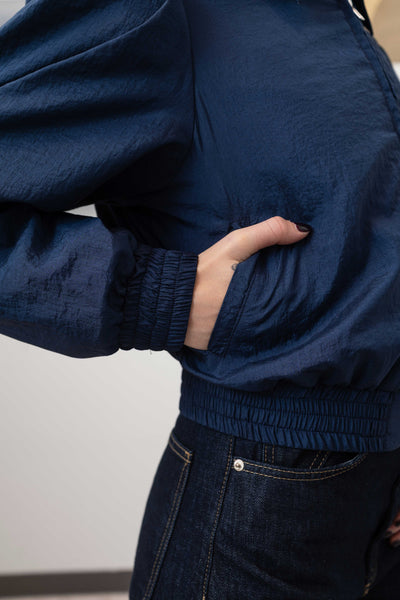 Sleeve detail of sculptural blouson jacket in navy — pleated volume with crinkled nylon surface and elasticized cuff, nowhere studio