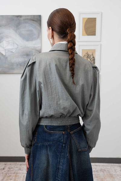 Close-up back detail of sculptural blouson jacket in silver — water-resistant nylon with sculptural gathered waist, nowhere studio