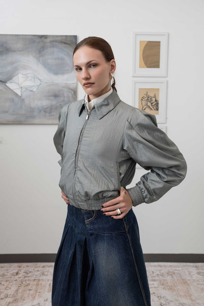 Close-up left side alternate detail of sculptural blouson jacket in silver — crinkled nylon texture with gathered waist seam, nowhere studio
