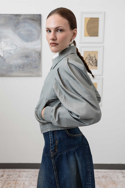 Close-up left side detail of sculptural blouson jacket in silver — pleated sleeve construction in water-resistant crinkled nylon, nowhere studio