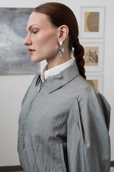 Front left detail of sculptural blouson jacket in silver pleated sleeves on crinkled nylon, nowhere studio